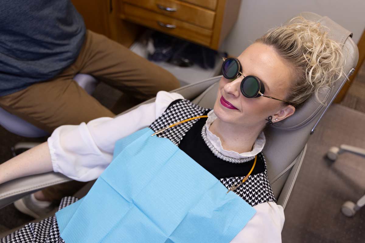 A woman wears MiOptics nbGL glasses for a dental procedure to help with dental anxiety.