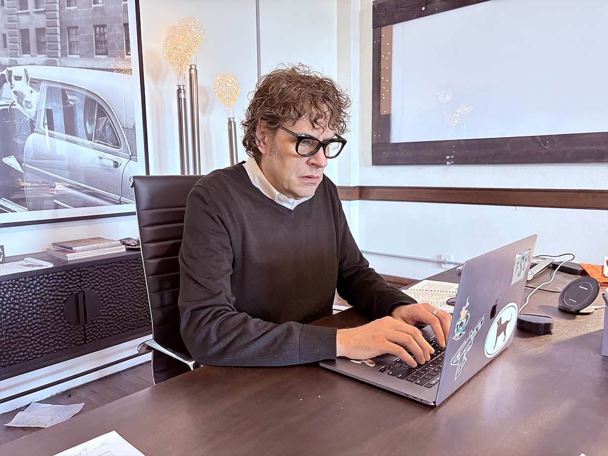 A man works on his computer while wearing MiClip glasses with a prescription lens.