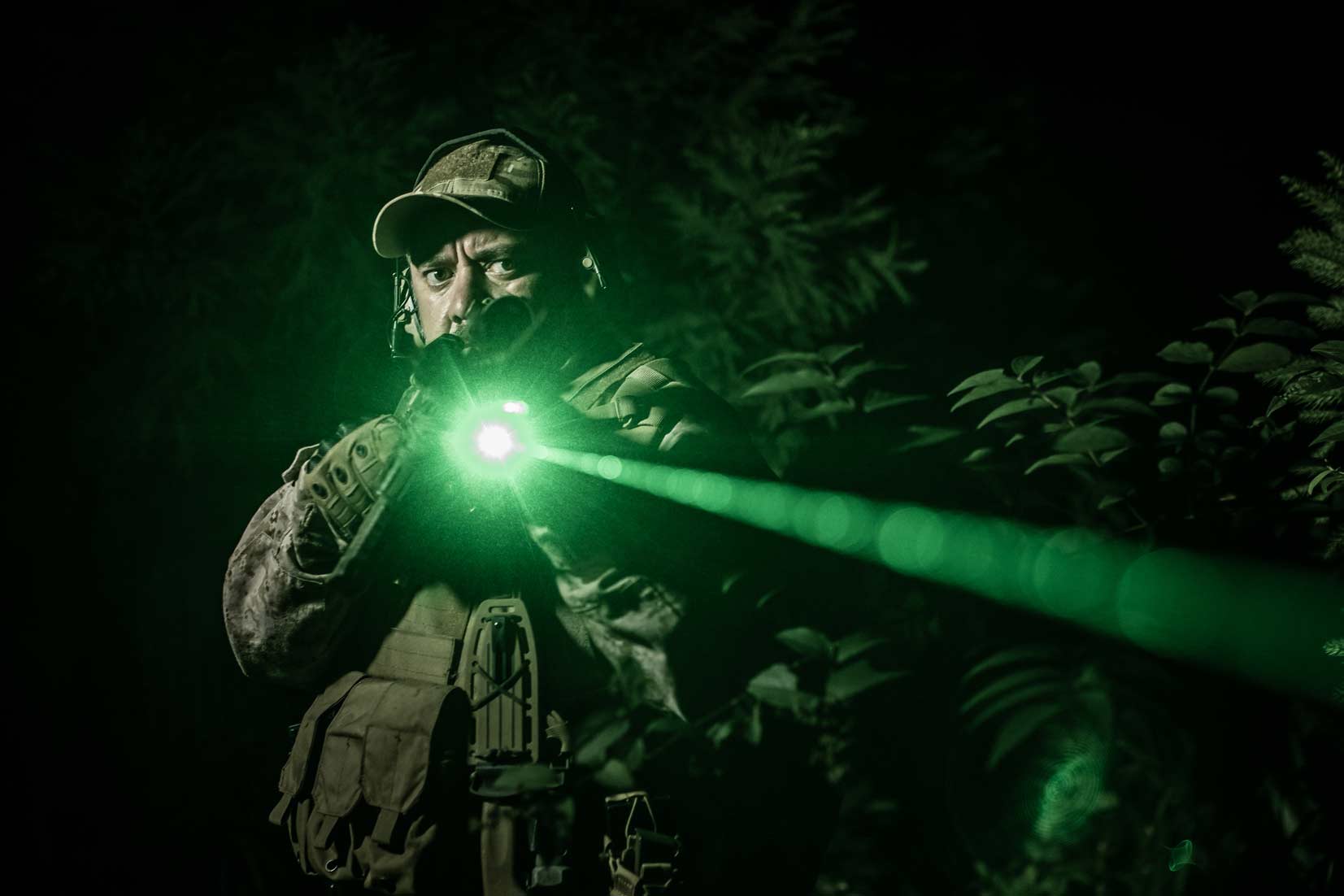A Navy SEAL aims with a laser sight at night.