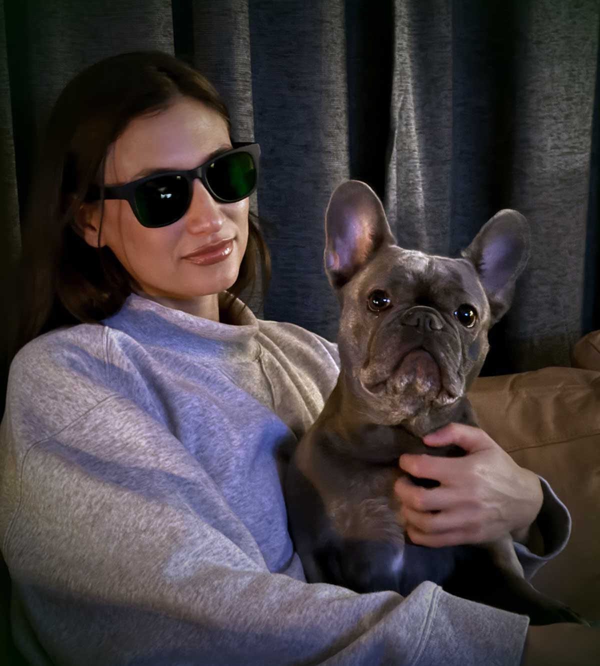A young woman wearing narrow band green light glasses chilling with her dog.